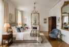 Classic Parisian elegance bedroom with herringbone floors, plush rug, gilded mirrors.