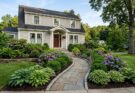 Tiered landscaping with hydrangeas and hostas, framing a home's facade and a clear pathway.
