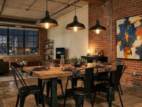 Industrial loft dining room with concrete floors, metal table, Tolix chairs, charcoal grey, deep browns, and abstract art.