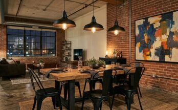 Industrial loft dining room with concrete floors, metal table, Tolix chairs, charcoal grey, deep browns, and abstract art.