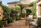 Mediterranean patio with terracotta tiles, wrought iron furniture, jasmine, olive trees, and a trickling fountain
