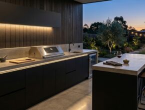 Modern minimalist outdoor kitchen with polished concrete, matte black cabinets, stainless steel grill, and warm LED lighting.