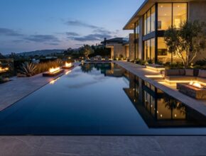 Modern architectural pool with perimeter overflow, mirror surface, integrated fire features, and sunken lounge.