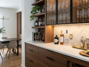Modern built-in buffet and bar area with quartz countertop, glass cabinets, and displayed stemware.
