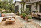 Patio divided into zones for dining and a cozy conversation nook, using an outdoor rug, furniture, and planters.