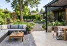 Backyard zones defined by an outdoor rug for a lounge area and different paving materials for dining and paths.