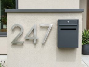 Modern oversized house numbers in brushed metal and a designer mailbox, enhancing a custom exterior facade.