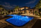 Nighttime pool area with mesmerizing underwater LED lights, subtle path lights, and accent lighting on trees