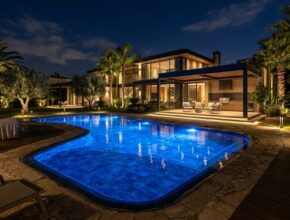 Nighttime pool area with mesmerizing underwater LED lights, subtle path lights, and accent lighting on trees