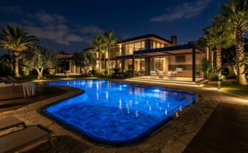 Nighttime pool area with mesmerizing underwater LED lights, subtle path lights, and accent lighting on trees