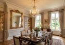 Dining room featuring elegant decorative molding and a large ornate mirror.