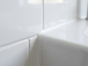 Close-up of freshly cleaned and re-grouted bathroom tiles and caulking.